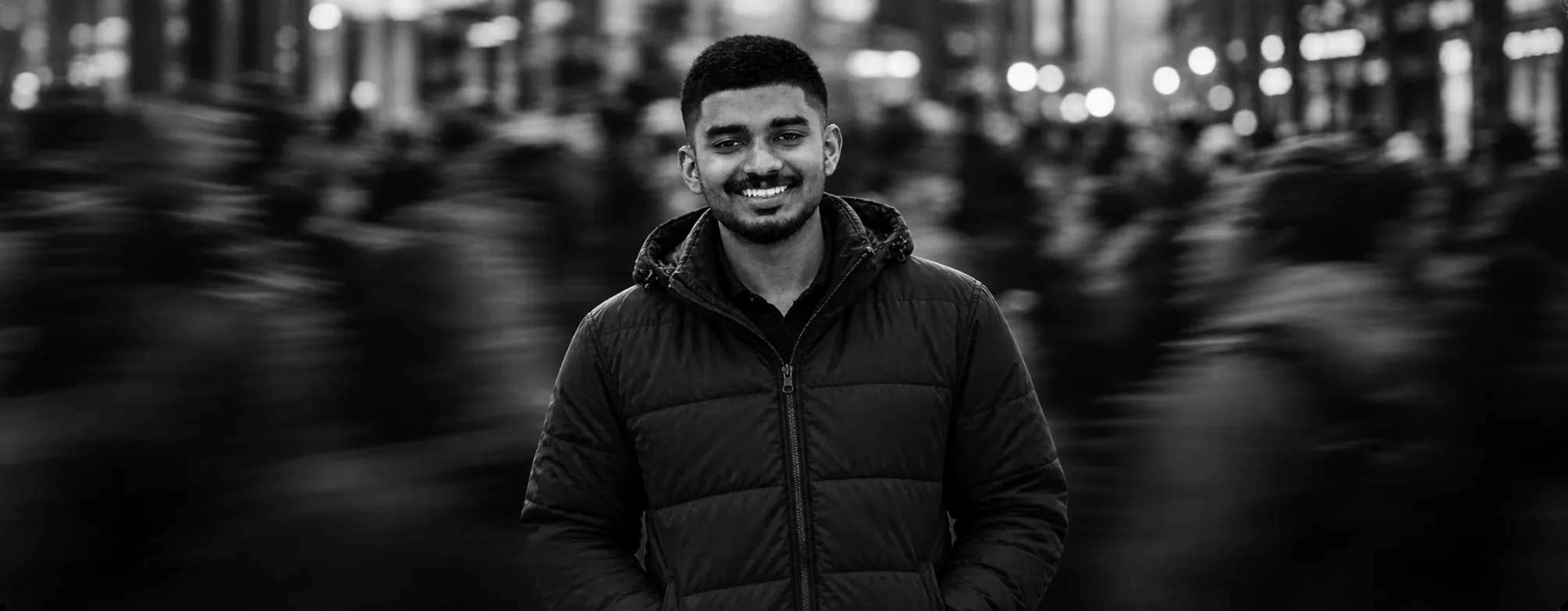 Shadi smiling in a busy city street at night, black and white